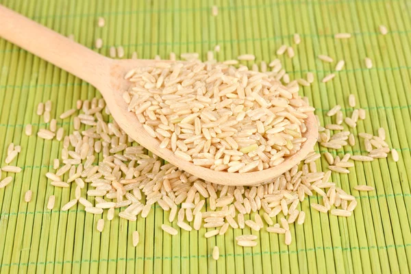 Reis in Holzlöffel auf Bambusmatte — Stockfoto
