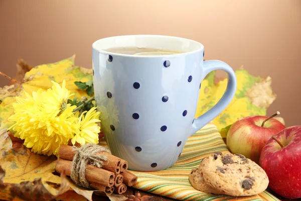 Tasse de thé chaud et feuilles d'automne, sur fond brun — Photo