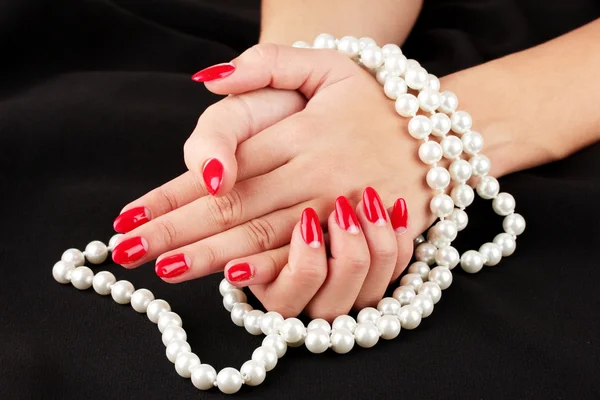 Female hands holding beads on color background — Stock Photo, Image