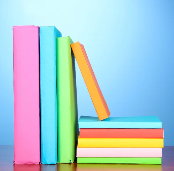 Stapel von bunten Büchern auf blauem Hintergrund — Stockfoto