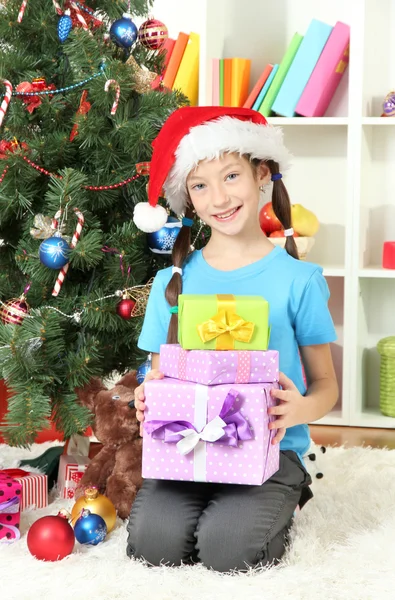 Klein meisje houden geschenkdozen in de buurt van de kerstboom — Stockfoto