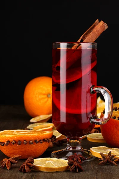 Vino caliente fragante en vaso con especias y naranjas en la mesa de madera —  Fotos de Stock