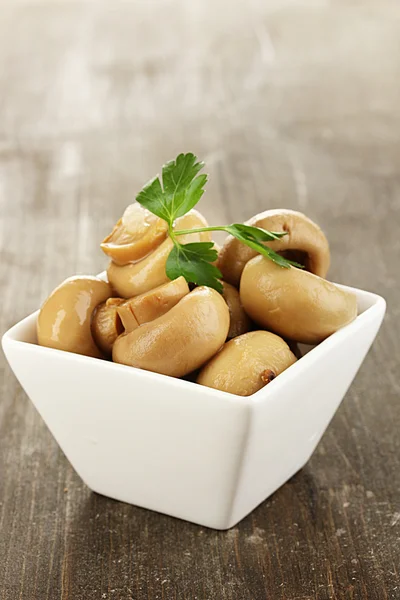 Delicious marinated mushrooms in bowl on wooden table close-up — Stock Photo, Image