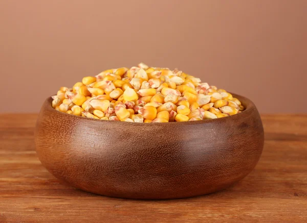 Corn in wooden bowl on table on brown background — Stock Photo, Image