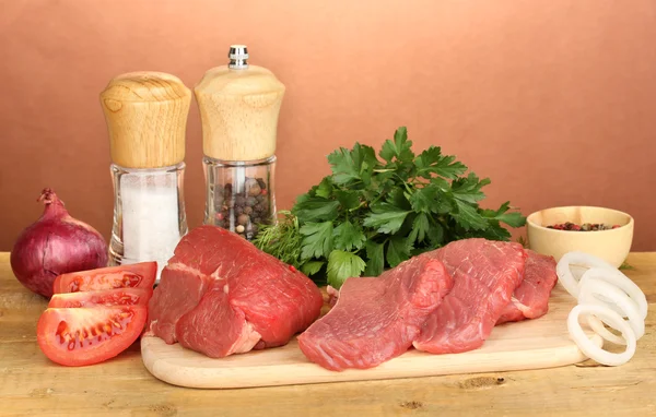 Carne de res cruda con especias en mesa de madera sobre fondo marrón —  Fotos de Stock