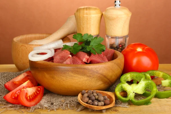 Ruwe rundvlees met kruiden en specerijen op houten tafel op bruine achtergrond — Stockfoto