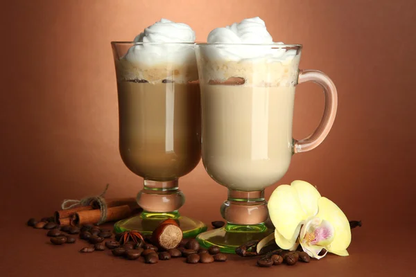 Café latte parfumé dans des tasses à verres avec des épices, sur fond brun — Photo