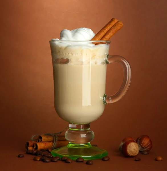 Fragrant coffee latte in glass cup with spices, on brown background — Stock Photo, Image