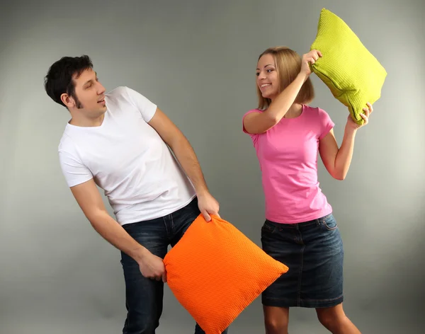 Young couple with pillows on grey background — Stock Photo, Image