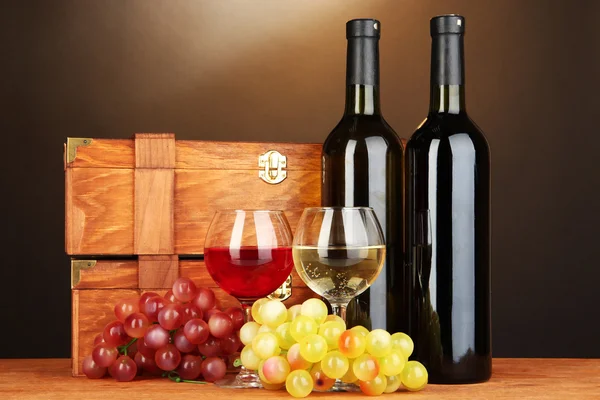 茶色の背景に木製のテーブルの上のワインのボトルを持つ木製ケース — ストック写真