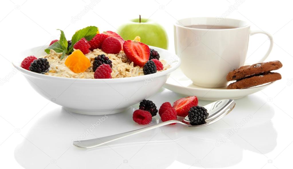 tasty oatmeal with berries and cup of tea, isolated on white