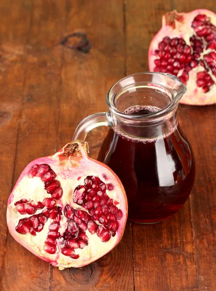 Caraffa piena di succo di melograno, su fondo di legno — Foto Stock