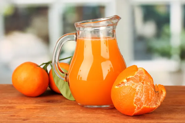 Kendi penuh jus jeruk, di atas meja kayu dengan latar belakang cerah — Stok Foto