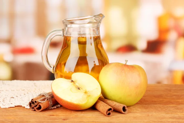 Jarro cheio de suco de maçã e maçã na mesa de madeira no fundo brilhante — Fotografia de Stock