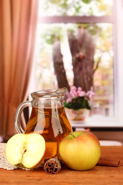 Full jug of apple juice and apple on wooden table on bright background — Stock Photo, Image