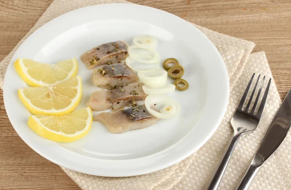 Dish of herring and lemon on plate on wooden table close-up — Stock Photo, Image