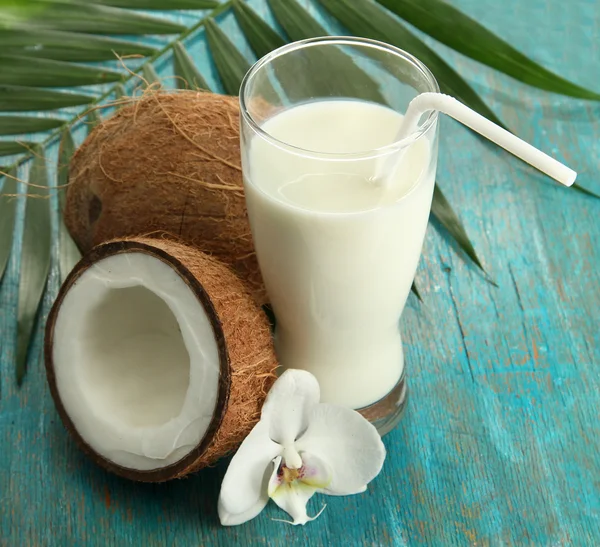 Kokosnoten met glas melk, op blauwe houten achtergrond — Stockfoto