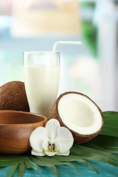 Coco con vaso de leche, sobre mesa de madera azul —  Fotos de Stock