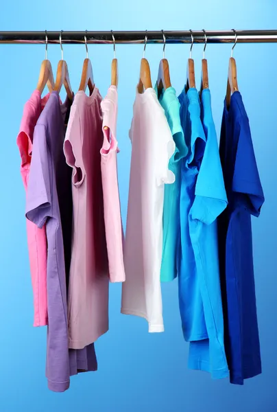 Variedade de camisas casuais em cabides de madeira, no fundo azul — Fotografia de Stock