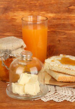 Bal tereyağı üzerinde cam daire cam kapak ve taze ekmek ile ahşap zemin üzerinde