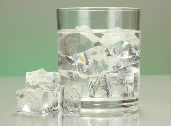 Cubos de hielo en vidrio sobre fondo verde claro — Foto de Stock