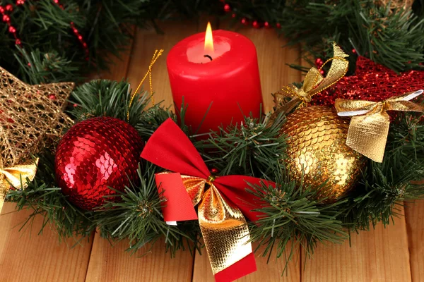 Christmas composition with candle and decorations in red and gold colors on wooden background — Stock Photo, Image