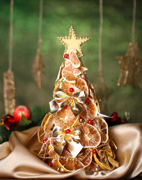 Prachtige Kerstboom van droge citroenen met decor, op glans groene achtergrond — Stockfoto