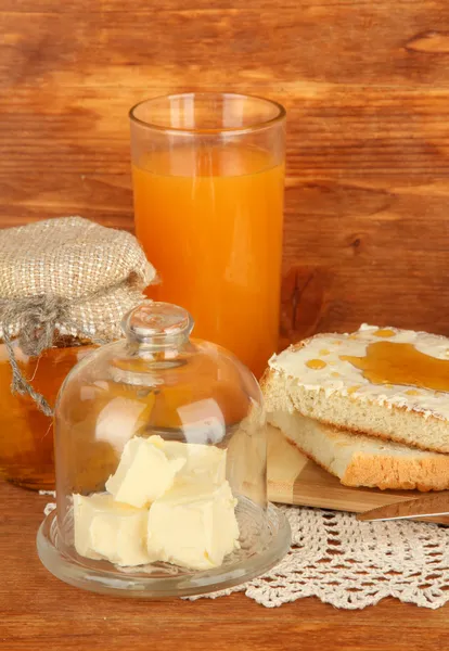 Butter on glass saucer with glass cover and fresh bread, honey on wooden background — Stock Photo, Image