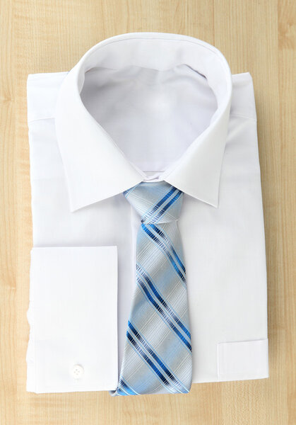 New white man's shirt with color tie on wooden background
