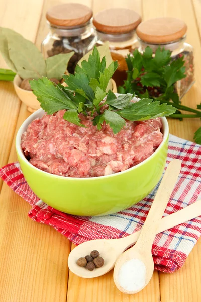 Bowl of raw ground meat with spices on wooden table Royalty Free Stock Images