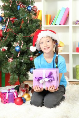 hediye kutusu Noel ağacının yakınında tutan küçük bir kız