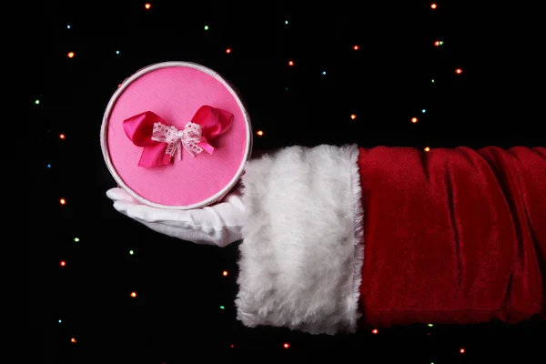 Santa Claus mano sosteniendo caja de regalo sobre fondo brillante — Foto de Stock