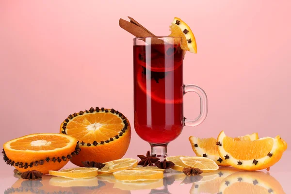 Fragrant mulled wine in glass with spices and oranges around on red background — Stock Photo, Image