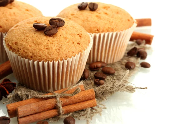 Smakelijke muffin gebak op jute, specerijen en koffie zaden, geïsoleerd op wit — Stockfoto