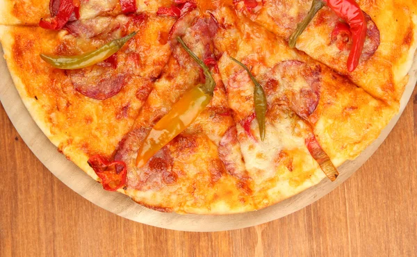 Gustosa pizza al salame su tavola di legno su fondo di legno — Foto Stock
