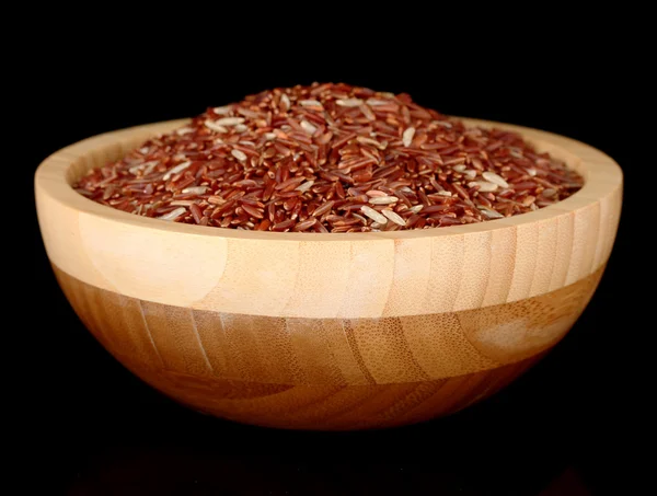 Red rice in wooden bowl isolated on black — Stock Photo, Image