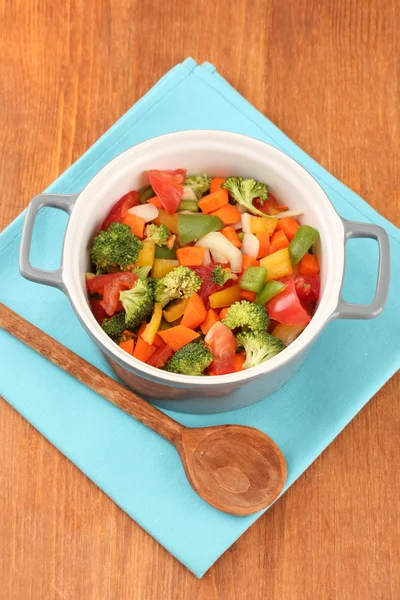 Ragoût de légumes en pot gris sur serviette de couleur sur fond en bois — Photo