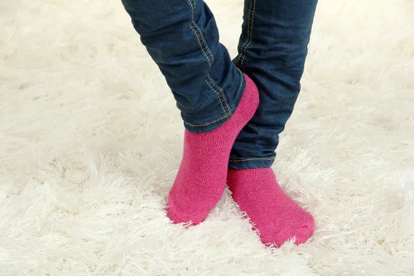 Женские ноги в разноцветных носках на белом фоне ковра — стоковое фото