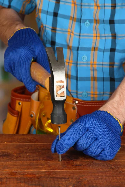 Les mains du constructeur martelant l'ongle dans le bois — Photo