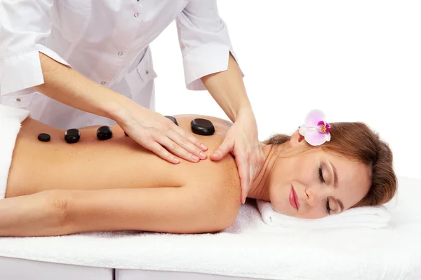 Beautiful woman in spa salon with spa stones getting massage, isolated on white — Stock Photo, Image