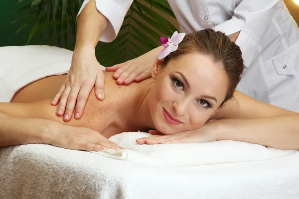 Schöne junge Frau im Wellness-Salon bekommt Massage, auf grünem Hintergrund — Stockfoto