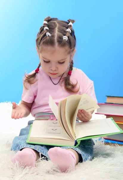 Carina bambina con libri colorati, su sfondo blu — Foto Stock