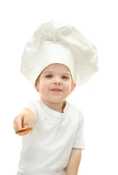Маленька дівчинка в капелюсі шеф-кухаря з ложкою, ізольована на білому — стокове фото