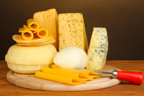 Vários tipos de queijo na mesa de madeira no fundo marrom — Fotografia de Stock