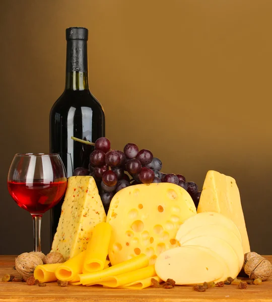 Various types of cheese on wooden table on brown background — Stock Photo, Image