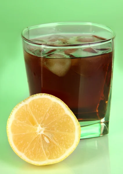 Glass of whiskey with ice and lemon on green background — Stock Photo, Image