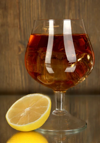 Vaso de brandy con hielo y limón sobre fondo de madera — Foto de Stock