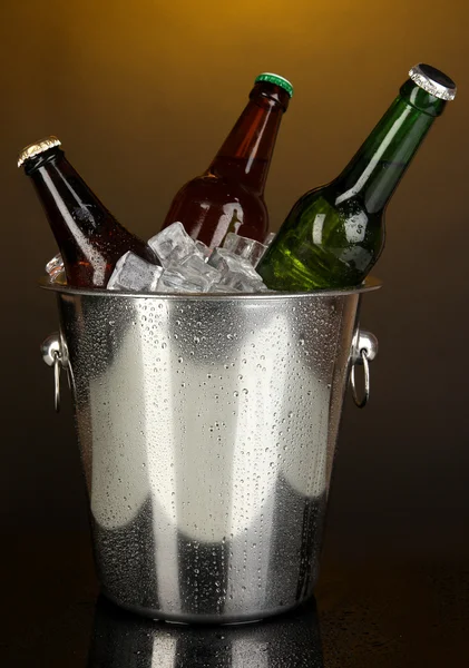 Botellas de cerveza en cubo de hielo sobre fondo amarillo darck —  Fotos de Stock