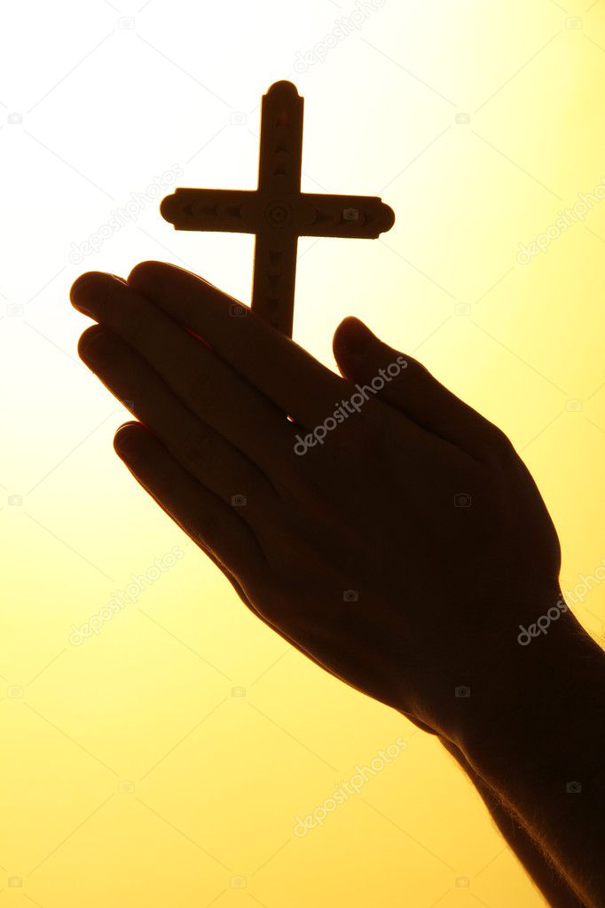 man hands with crucifix, on yellow background