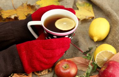 fincan sıcak içecek ve sonbahar yaprakları, çuval bezi arka planda tutan eller